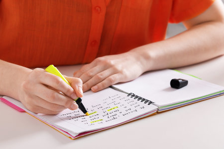 Woman highlighting important information at white desk indoors, closeup