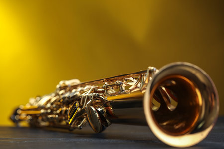 Jazz. One beautiful saxophone on black table against color background, closeup