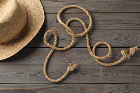 Cotton rope and straw hat on wooden background, flat lay