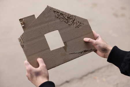 Homeless man with carton house figure outdoors, closeupの写真素材