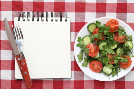 Blank recipe book, salad and cutlery on checkered tablecloth, top view. Mockup for designの写真素材