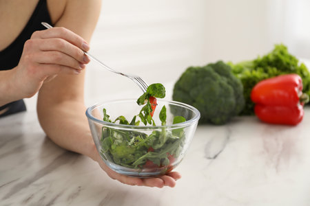 Woman in fitness clothes with salad at white marble table indoors, closeup. Healthy foodの写真素材