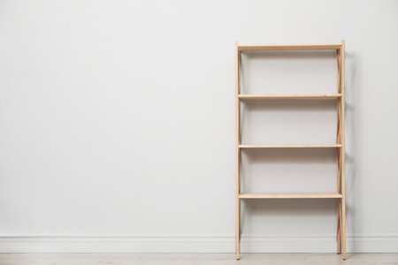 Empty wooden shelving unit near light grey wall indoors. Space for textの写真素材