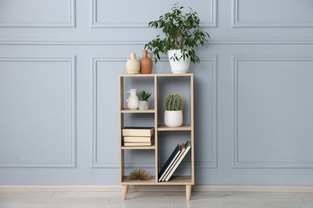 Shelving unit with houseplants and other decor near gray wallの写真素材