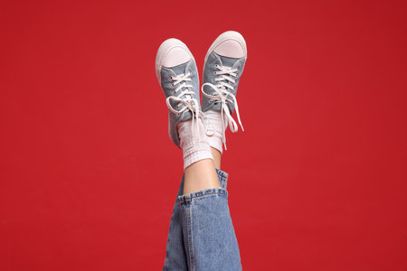 Woman wearing stylish sneakers on red background, closeupの写真素材