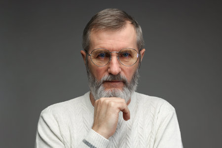 Portrait of mature man in glasses on gray background