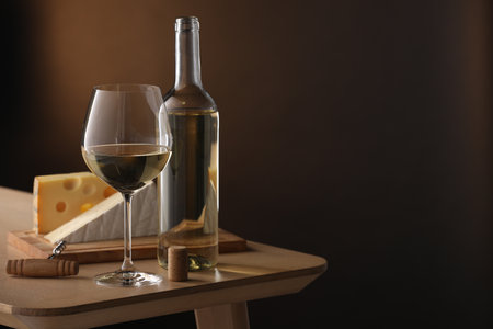 Tasty wine and cheese on wooden table against brown gradient background. Space for textの写真素材