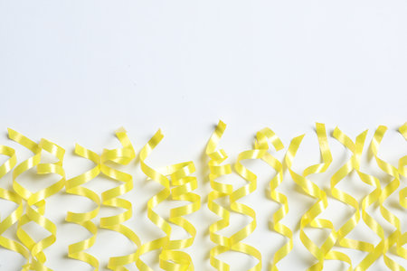 Yellow serpentine streamers on white background, top viewの写真素材