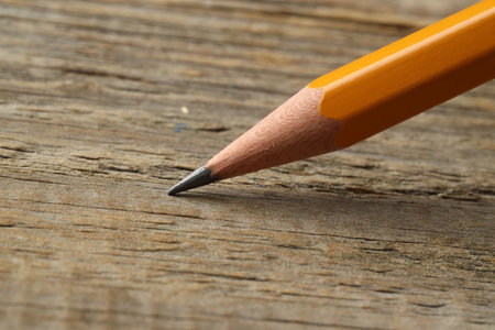 One sharp graphite pencil on wooden table, closeup. Space for textの写真素材