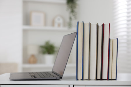 Different book and laptop on white desk indoors. Space for textの写真素材
