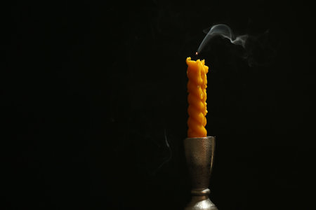 Extinguished candle in candlestick on black background, space for textの写真素材