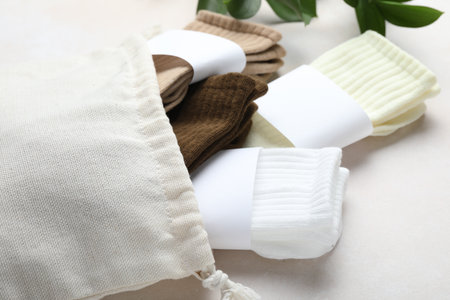 Different soft socks, bag and leaves on light beige background, closeupの写真素材