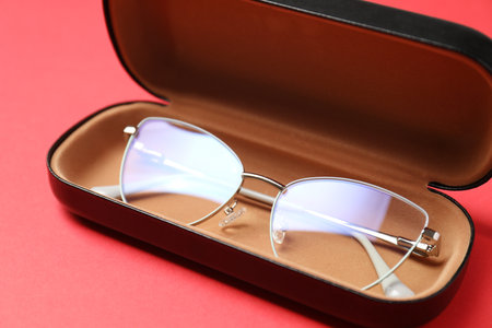 Case with stylish glasses on red background, closeupの写真素材