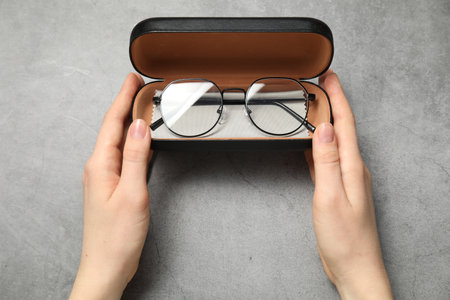 Woman with glasses in case on grey background, top viewの写真素材