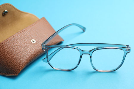 Case with stylish glasses on light blue background, closeupの写真素材