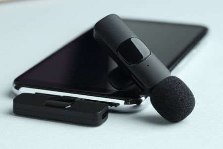 Lavalier microphone and smartphone with wireless receiver on light background, closeupの写真素材