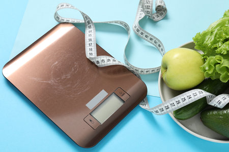 Electronic kitchen scale, measuring tape and products on light blue background, above view. Dietの写真素材