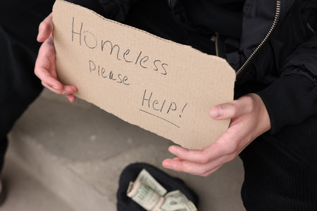 Man with sign Homeless please help and money outdoors, closeupの写真素材