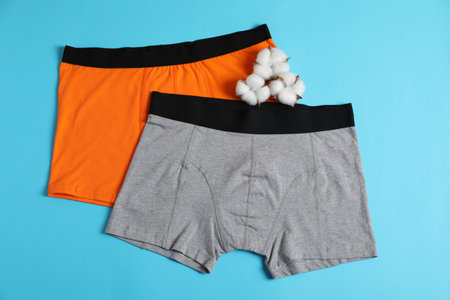 Comfortable men's underwear and cotton flowers on light blue background, top viewの写真素材
