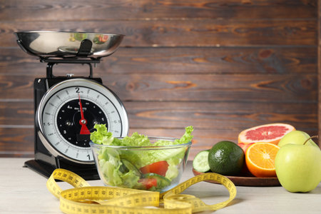 Kitchen scales, products and measuring tape on white wooden tableの写真素材