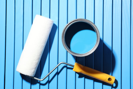 Can of bright paint and roller on light blue wooden table, flat layの写真素材