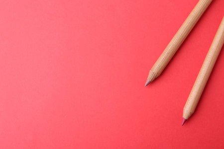 Two lip pencils on red background, top view. Space for textの写真素材
