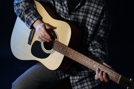 Woman playing guitar on black background, closeupの写真素材