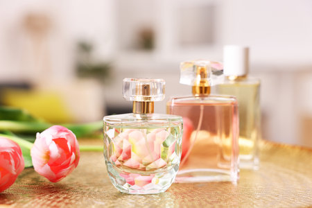 Bottles of aromatic perfume and flowers on textured plate against blurred background, closeupの写真素材