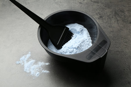 Bowl with hair bleaching powder and brush on gray table, closeupの写真素材