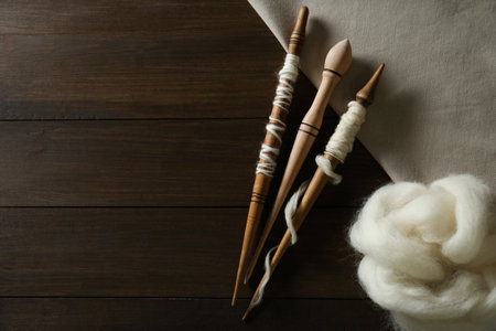 Soft white wool with spindles on wooden table, flat lay. Space for textの写真素材