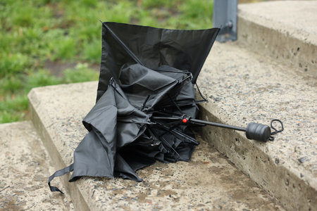 Broken black umbrella on wet stairs outdoorsの写真素材
