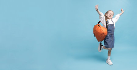 Cute schoolgirl with backpack on light blue background, space for text. Bannerの写真素材