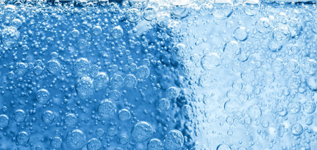 Soda water with bubbles and ice cube as background, closeupの写真素材