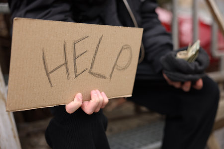 Homeless man holding sign with word Help and money outdoors, selective focusの写真素材