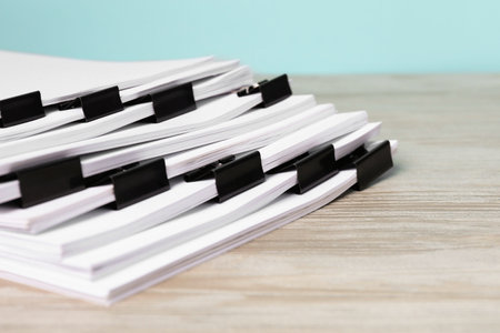 Binder clips with sheets of paper on wooden table, closeupの写真素材