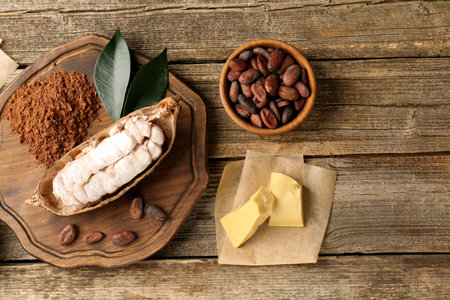 Cocoa pod with beans, powder and butter on wooden table, flat layの写真素材