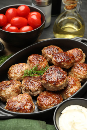 Delicious patties in baking dish, spices and tomatoes on table, closeupの写真素材