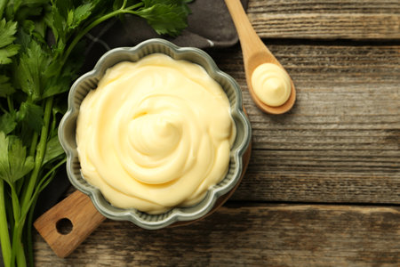 Delicious mayonnaise sauce in bowl and parsley on wooden table, top view. Space for textの写真素材