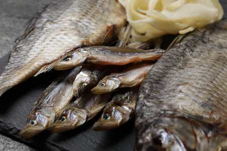 Many different dried fish snacks on gray table, closeup