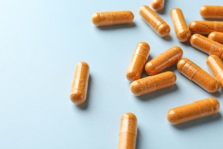 Turmeric capsules on light blue background, closeup. Space for textの写真素材