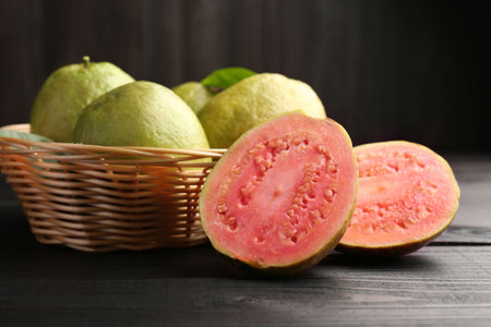 Fresh whole and cut guava fruits on black wooden table, closeupの写真素材