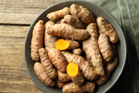 Tumeric rhizomes in bowl on wooden table, top viewの写真素材