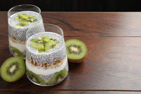 Superfood. Delicious dessert with chia seeds, yogurt, granola and kiwi on wooden table, closeup. Space for textの写真素材