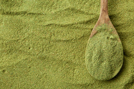 Superfood. Green powder and spoon, top view