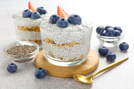 Delicious pudding with chia seeds, yogurt, blueberries, granola and strawberry on light grey table, closeup. Superfoodの写真素材