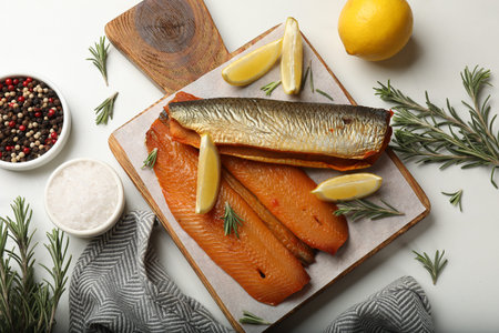 Smoked herrings and spices on white table, flat lay