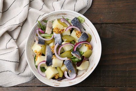 Delicious salad with herring, vegetables and mustard in bowl on wooden table, top viewの写真素材