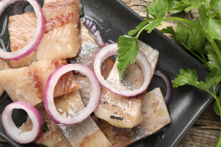 Pieces of herring with onions and parsley on wooden table, flat layの写真素材