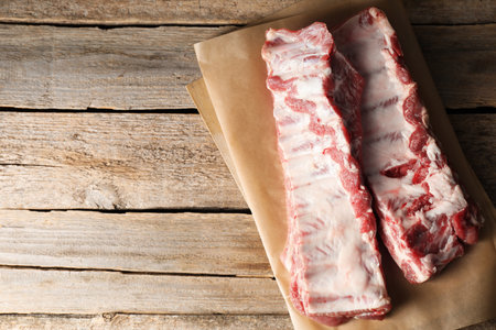 Raw pork ribs on wooden table, top view. Space for textの写真素材