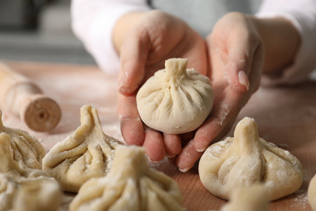 Woman making khinkali on table in kitchen, closeupの写真素材